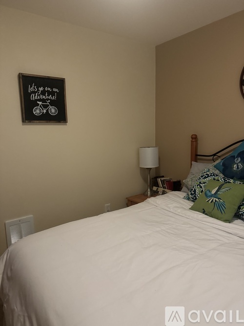 A bedroom with a white bed and a chalkboard sign on the wall.