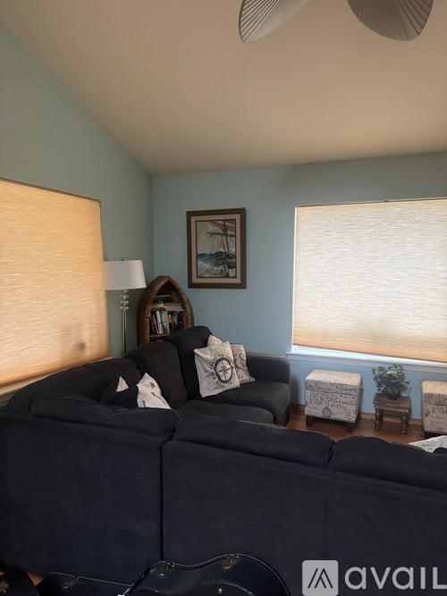A living room with a black couch and a fan on the ceiling.