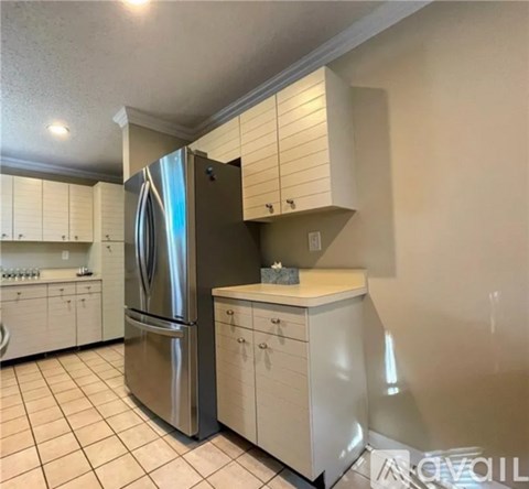 A kitchen with a stainless steel refrigerator and white cabinets.