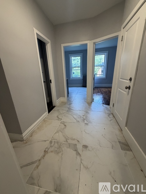 A hallway with marble flooring and white walls.