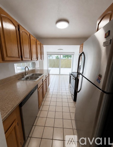 A kitchen with a refrigerator, sink, and cabinets.