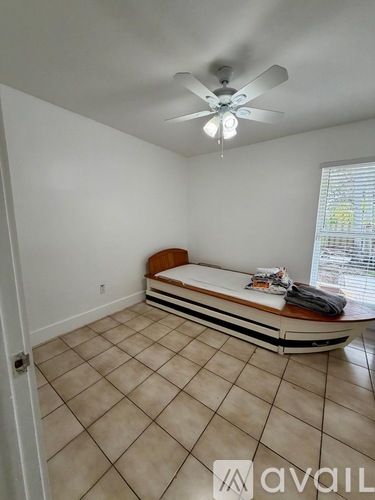 A bedroom with a bed, a ceiling fan, and a window with blinds.