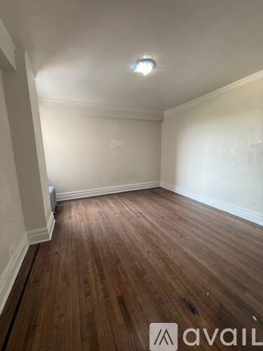 A room with wooden flooring and white walls.