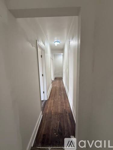 A long hallway with wooden floors and white walls.