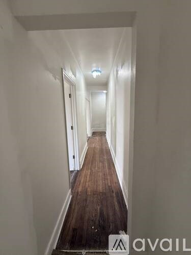 A long hallway with wooden floors and white walls.