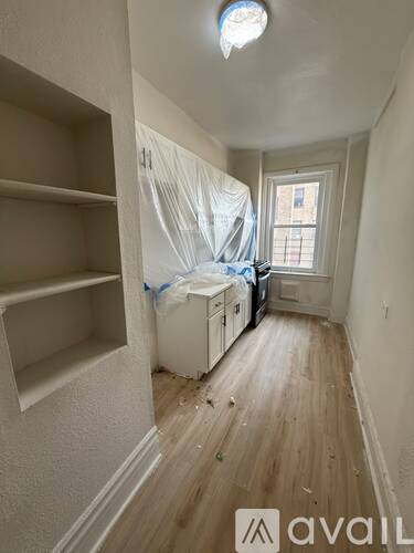 A room with wooden floors and a window covered in plastic.