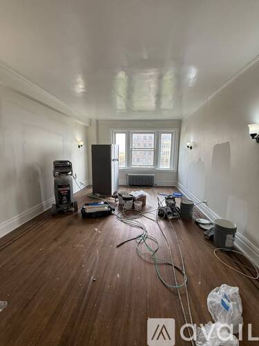 A room with wood flooring and a window is being renovated.