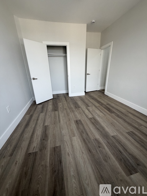 A room with wooden flooring and two doors.