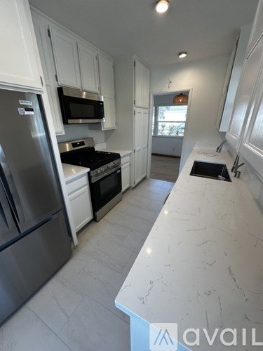 A kitchen with white cabinets and a marble counter top.