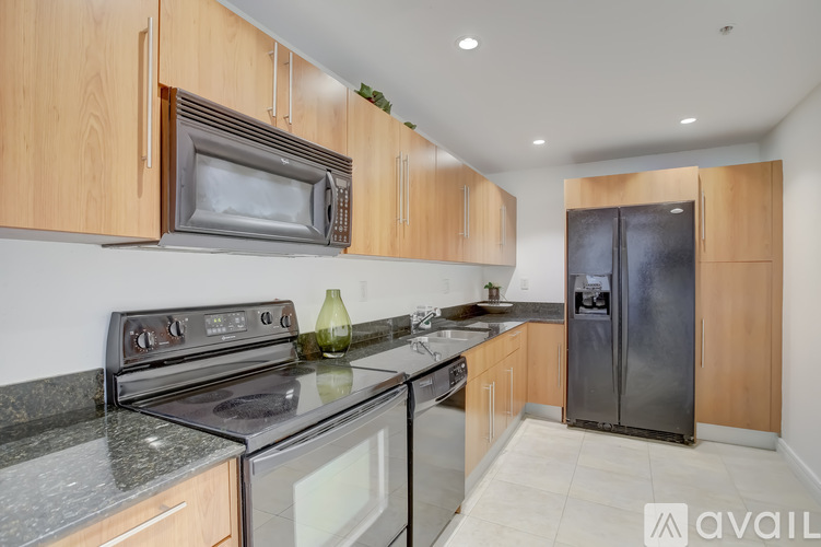 A kitchen with wooden cabinets and a black refrigerator.