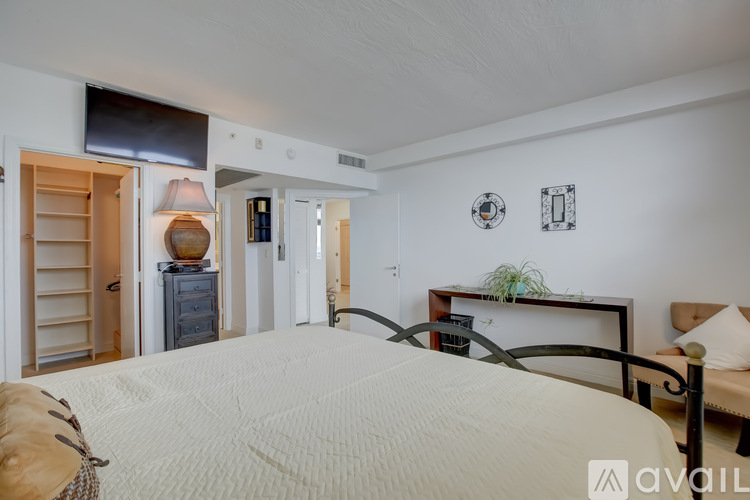 A bedroom with a large bed and a dresser with a lamp on it.