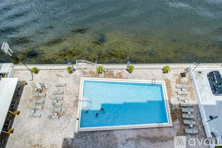 A small swimming pool surrounded by concrete and a few chairs.