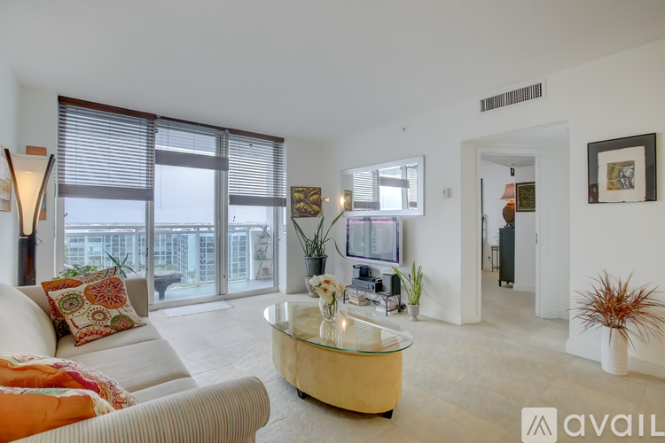 A living room with a glass coffee table and a couch with a throw pillow.