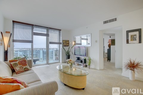 A living room with a glass coffee table and a couch with a throw pillow.