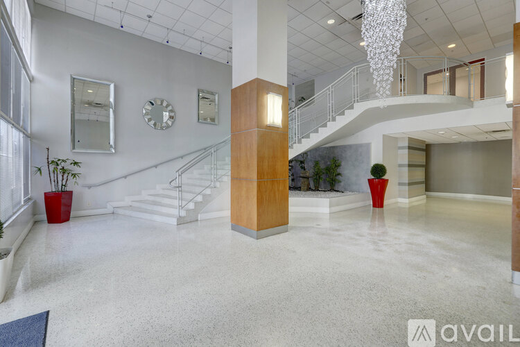 A spacious lobby with a staircase, a chandelier, and a reception desk.