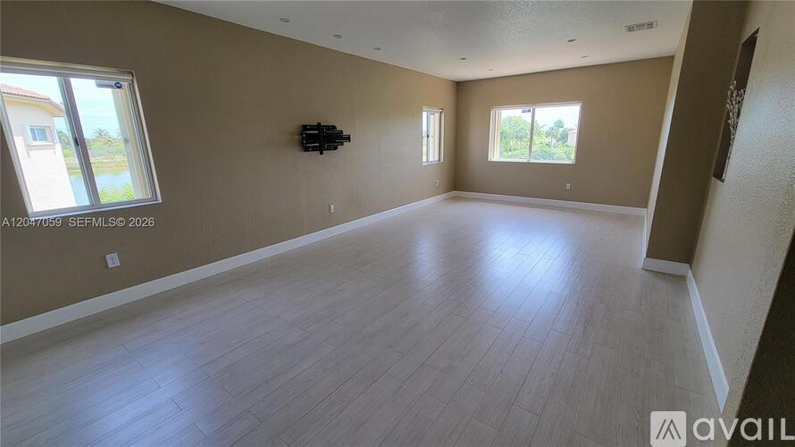 A spacious room with wooden flooring and a large window.