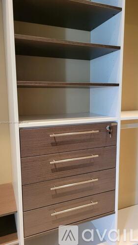 A white kitchen cabinet with brown drawers and shelves.
