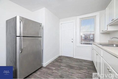 A kitchen with a stainless steel refrigerator and white cabinets.