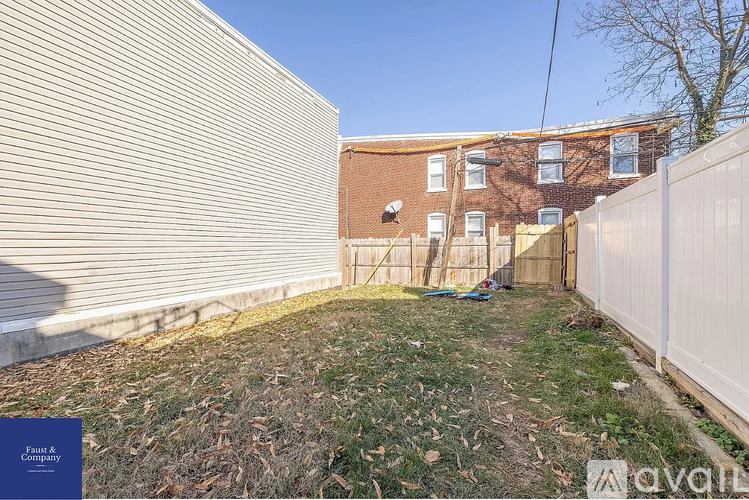 A backyard with a fence and a building in the background.