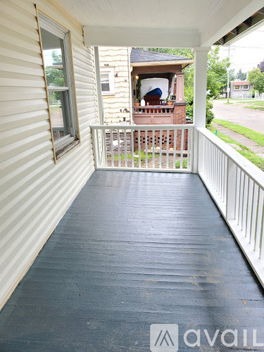 A porch with a white railing and a black floor.