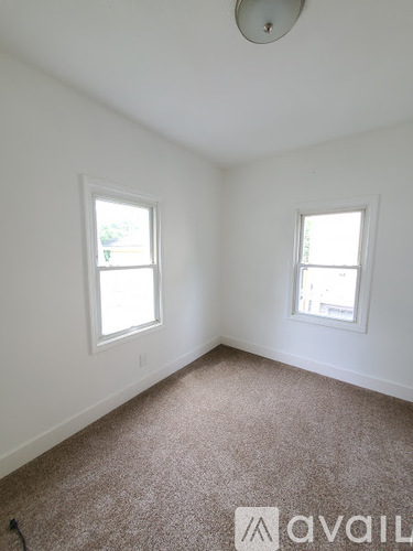 A room with two windows and carpeted floor.