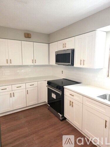 A kitchen with white cabinets and a black stove top oven.