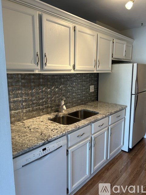 A kitchen with white cabinets and a granite countertop.