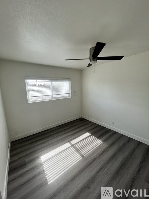 A room with a ceiling fan and a window letting in sunlight.