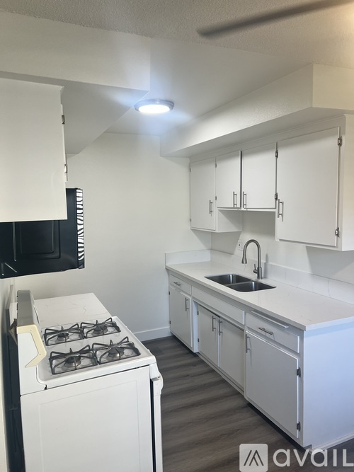 A kitchen with white cabinets and a stove top oven.