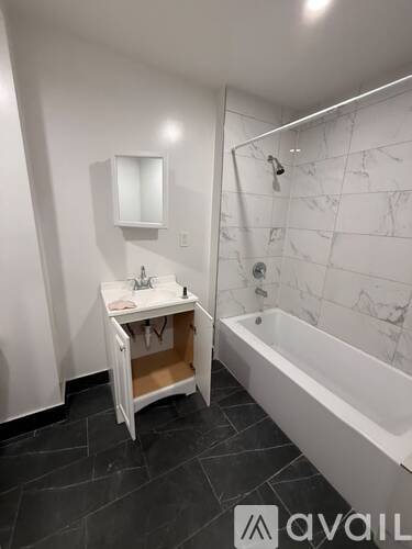 A bathroom with a marble wall and a white tub.