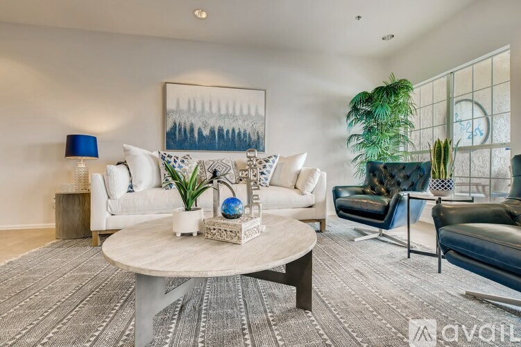 A living room with a white couch, a coffee table, and a painting on the wall.