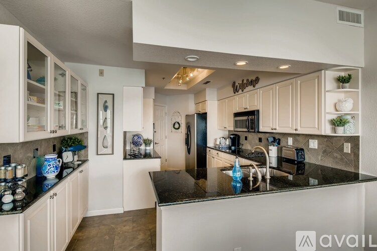 A kitchen with white cabinets and a black countertop.