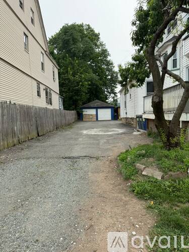 A gravel driveway leads to a garage in front of a house.