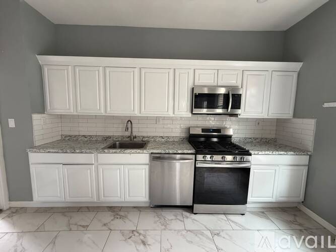 A kitchen with white cabinets and a marble countertop.