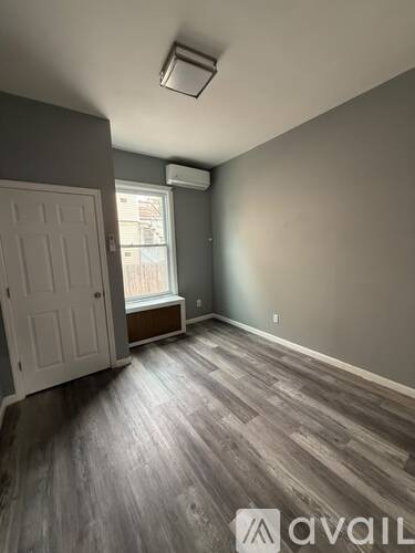 A room with a white door and a window with a view of a building outside.
