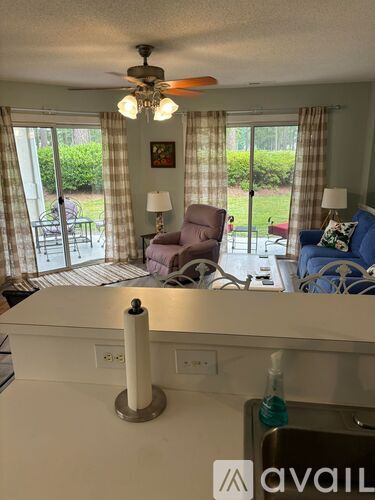 A living room with a ceiling fan and sliding glass doors.