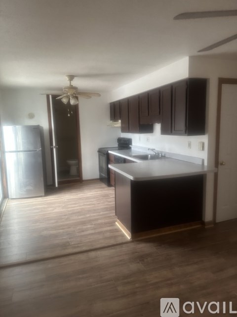 A kitchen with dark wood cabinets and a stainless steel refrigerator.
