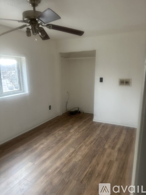 A room with a ceiling fan and wooden flooring.