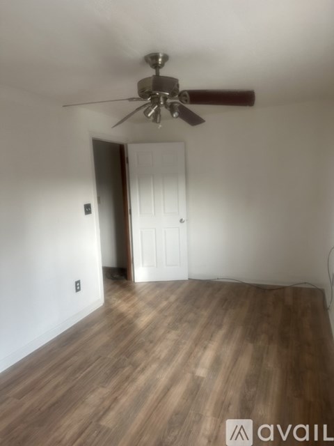 A room with a ceiling fan and wooden flooring.
