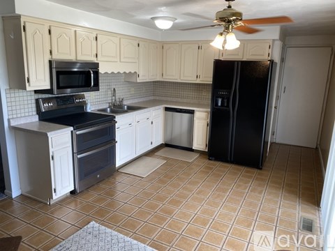 A kitchen with a black refrigerator and white cabinets.