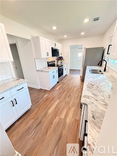 A modern kitchen with white cabinets and a wooden floor.