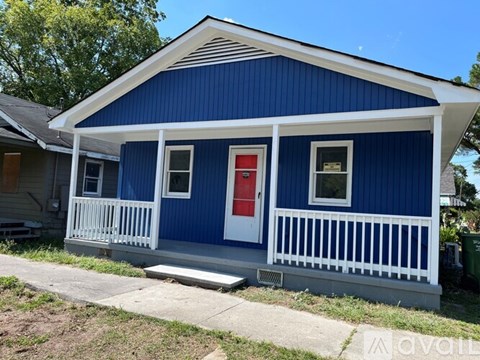 A blue house with a red door and white railings.