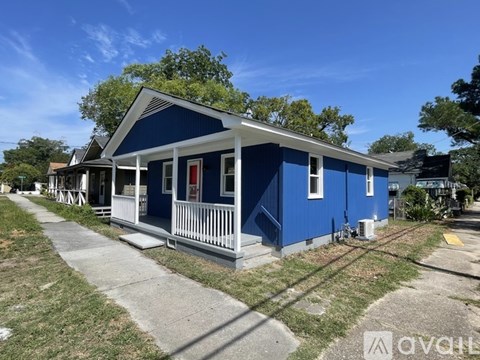 A blue house with a red door and white porch.