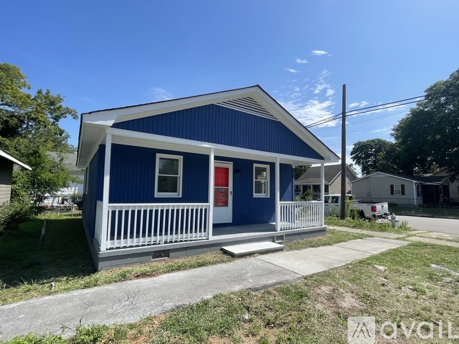 A blue house with a red door and a white porch.