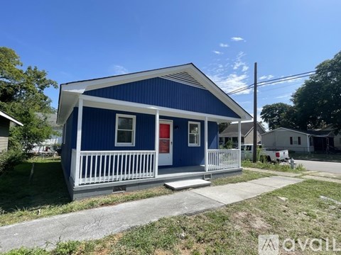 A blue house with a red door and a white porch.