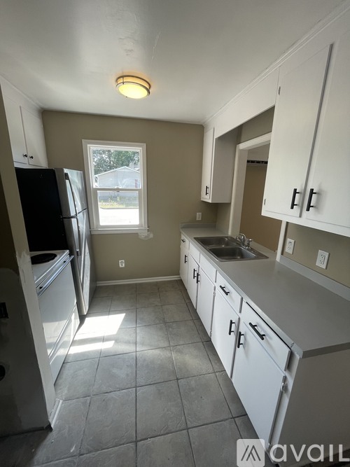 A kitchen with white cabinets and a black fridge.