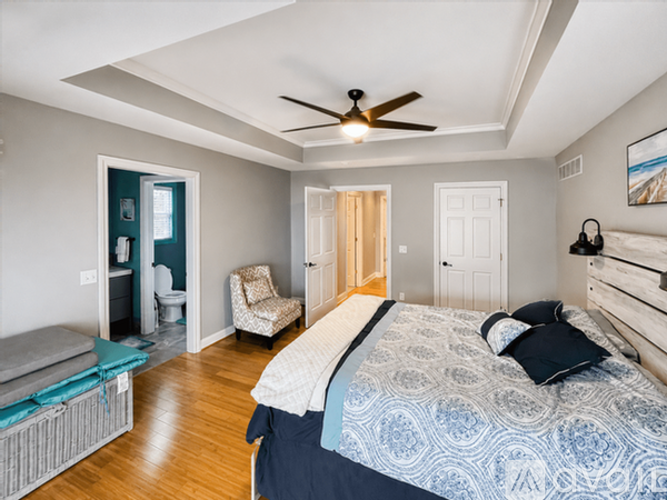 A bedroom with a bed, chair, and a ceiling fan.