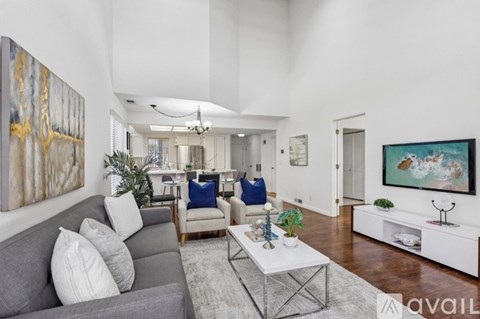 A living room with a grey sofa, a white coffee table, and a painting on the wall.