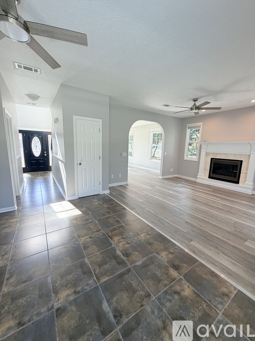 A spacious living room with a fireplace and a ceiling fan.