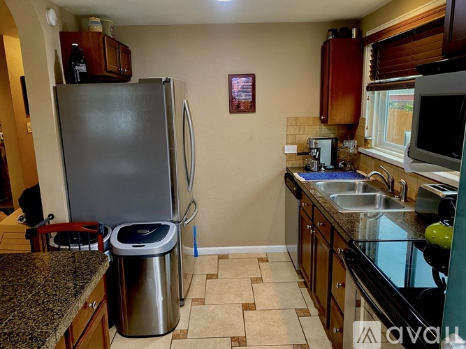 A kitchen with a black fridge and a black counter top.